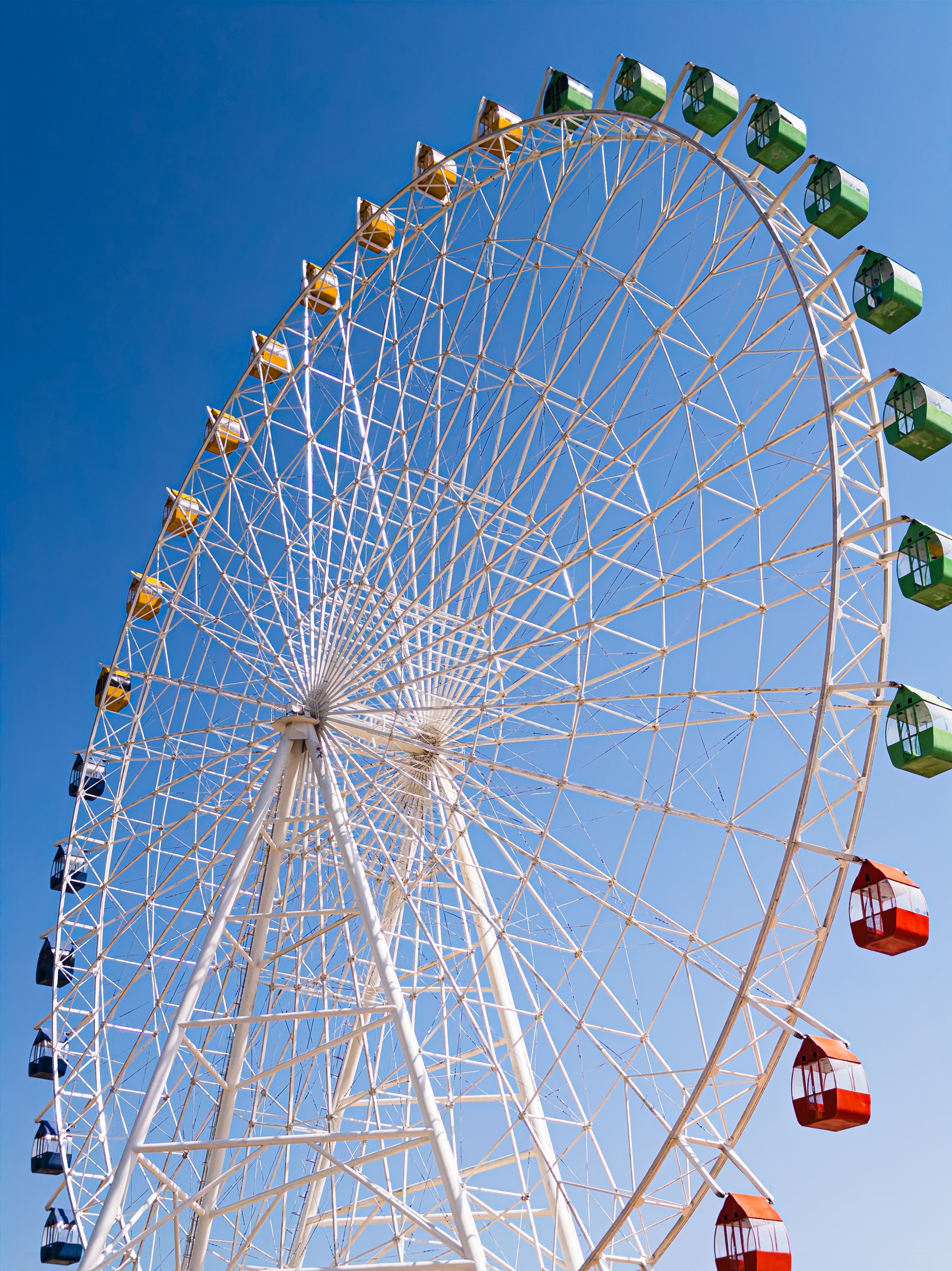 Vibrant Ferris wheel silhouetted against a clear blue sky in Bosteri, Kyrgyzstan.
