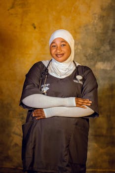 Portrait of a smiling female healthcare worker in scrubs with arms crossed and stethoscope.