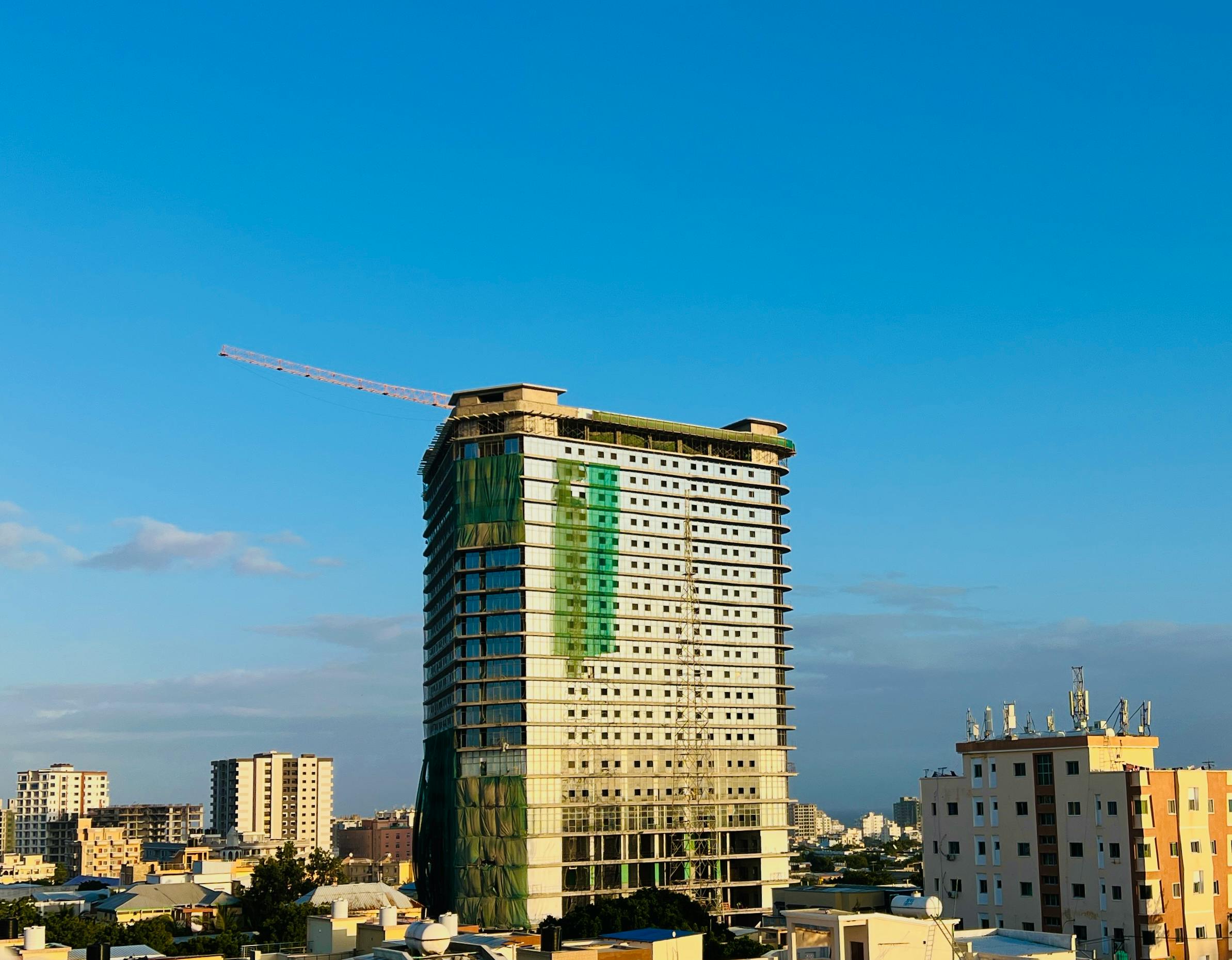 A tall building under construction in Mogadishu, showcasing the skyline against a clear blue sky.