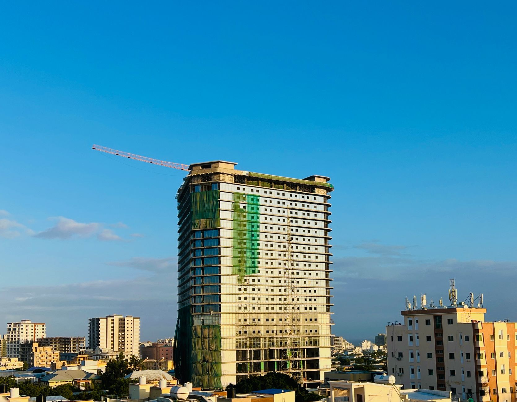 A tall building under construction in Mogadishu, showcasing the skyline against a clear blue sky.