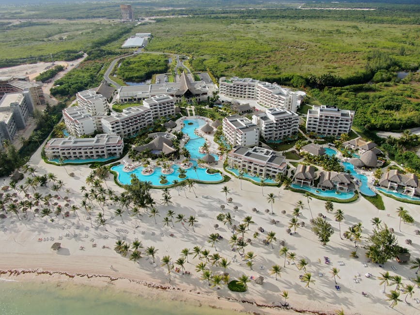 Aerial view of a luxurious beachfront resort with stunning pool and beachside amenities.
