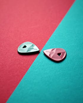 两个彩色吉他拨片置于绿色和粉色背景上，创意静物