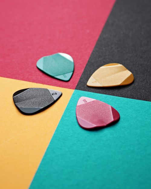 Free Diverse guitar picks on vibrant overlapping colored paper surfaces, showcasing musical accessories. Stock Photo
