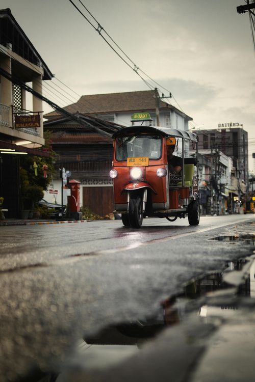 Free A traditional tuk-tuk driving through the rainy streets of Bangkok, Thailand, showcasing urban culture. Stock Photo