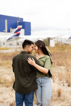 A couple embracing outdoors near an airport with airplanes in São Paulo, Brazil.
