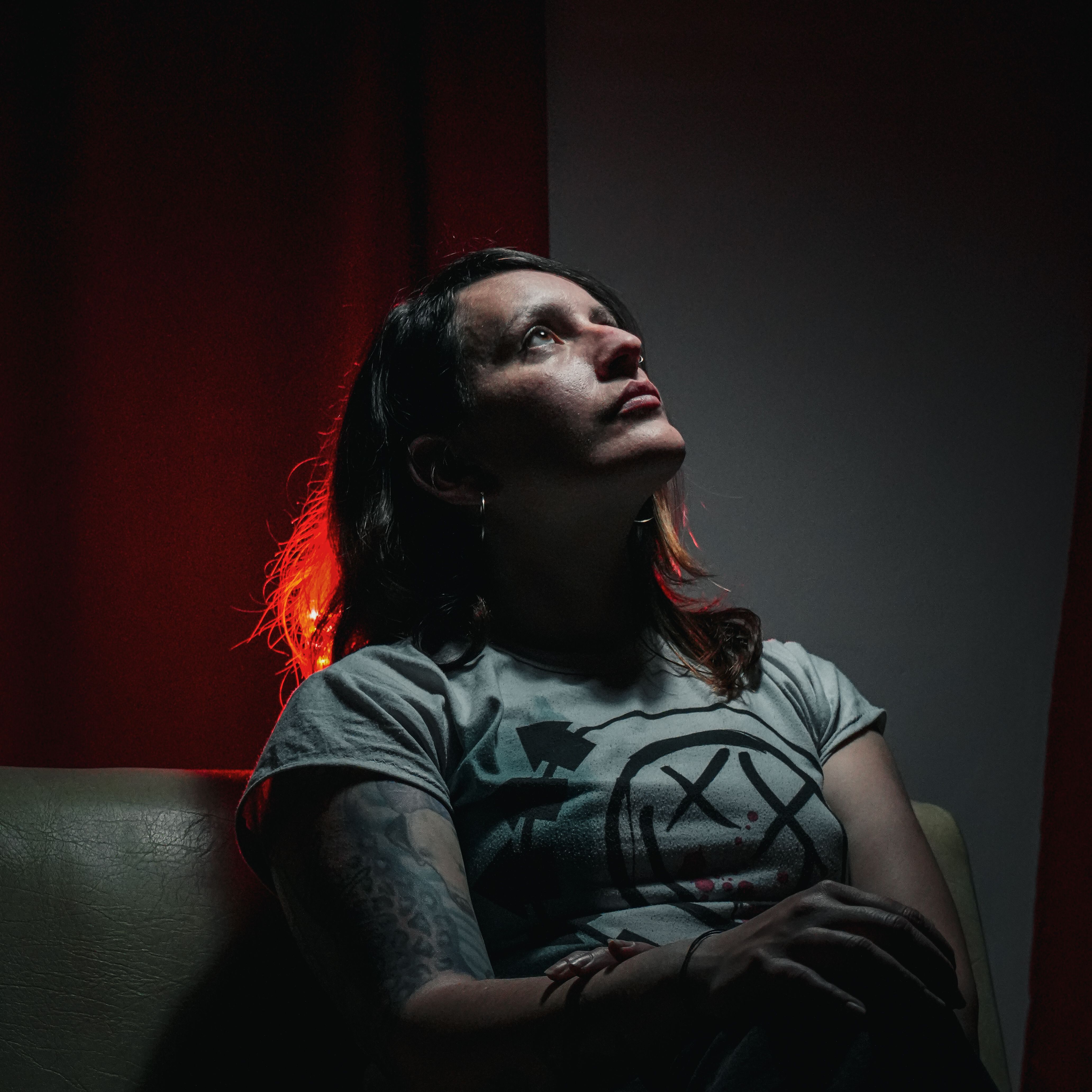 A contemplative woman sits under dramatic lighting, creating a moody atmosphere.