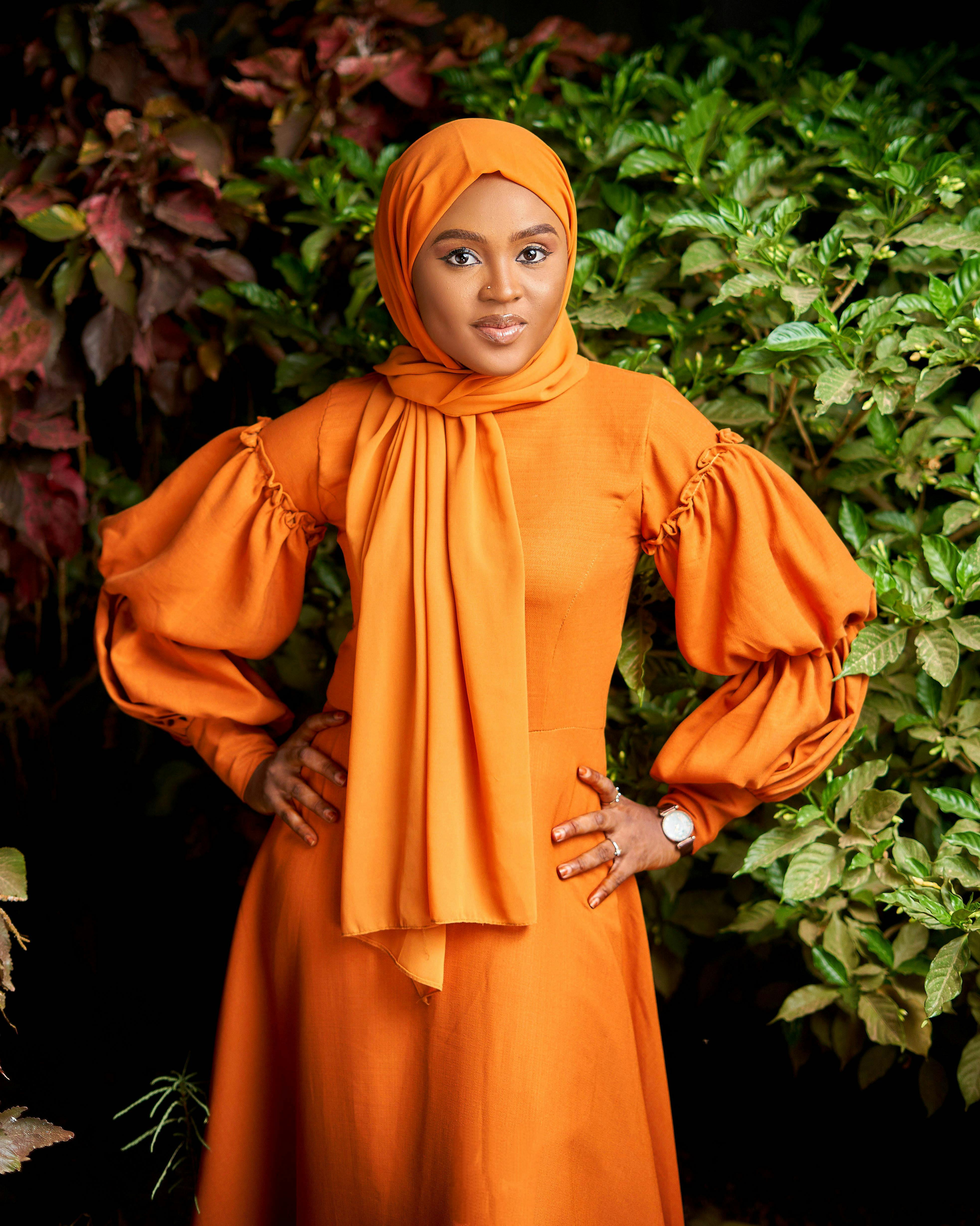 Gratuit Portrait saisissant d'une femme portant une abaya orange entourée d'une verdure vibrante au Nigéria. Photos