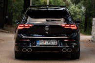 Sleek Black Car on a Serene Forest Road