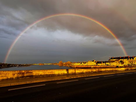 A stunning rainbow stretches over the Loire River, captured during the golden hour in a French town.