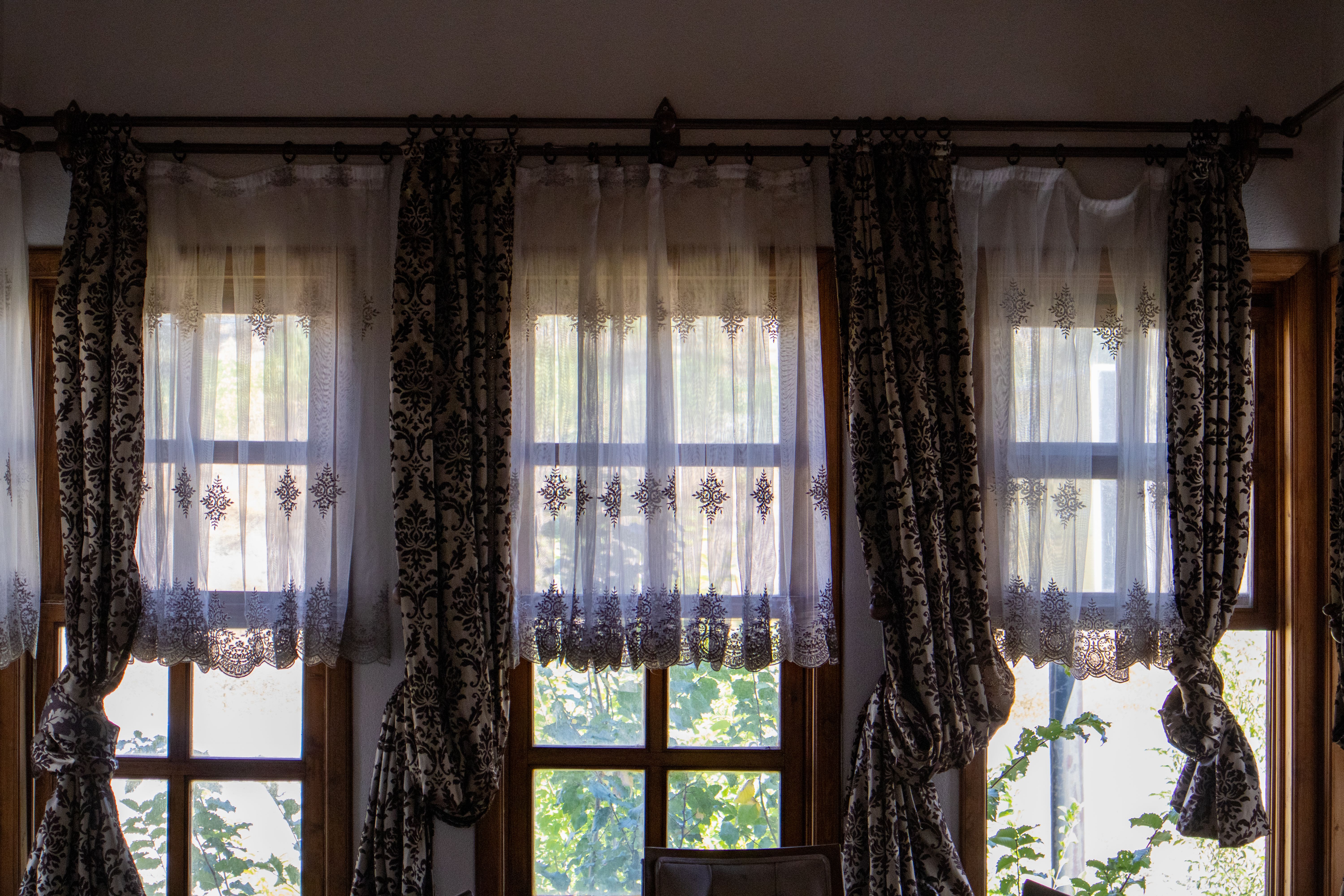 Free Sunlit room with elegant traditional curtains overlooking a garden view. Stock Photo