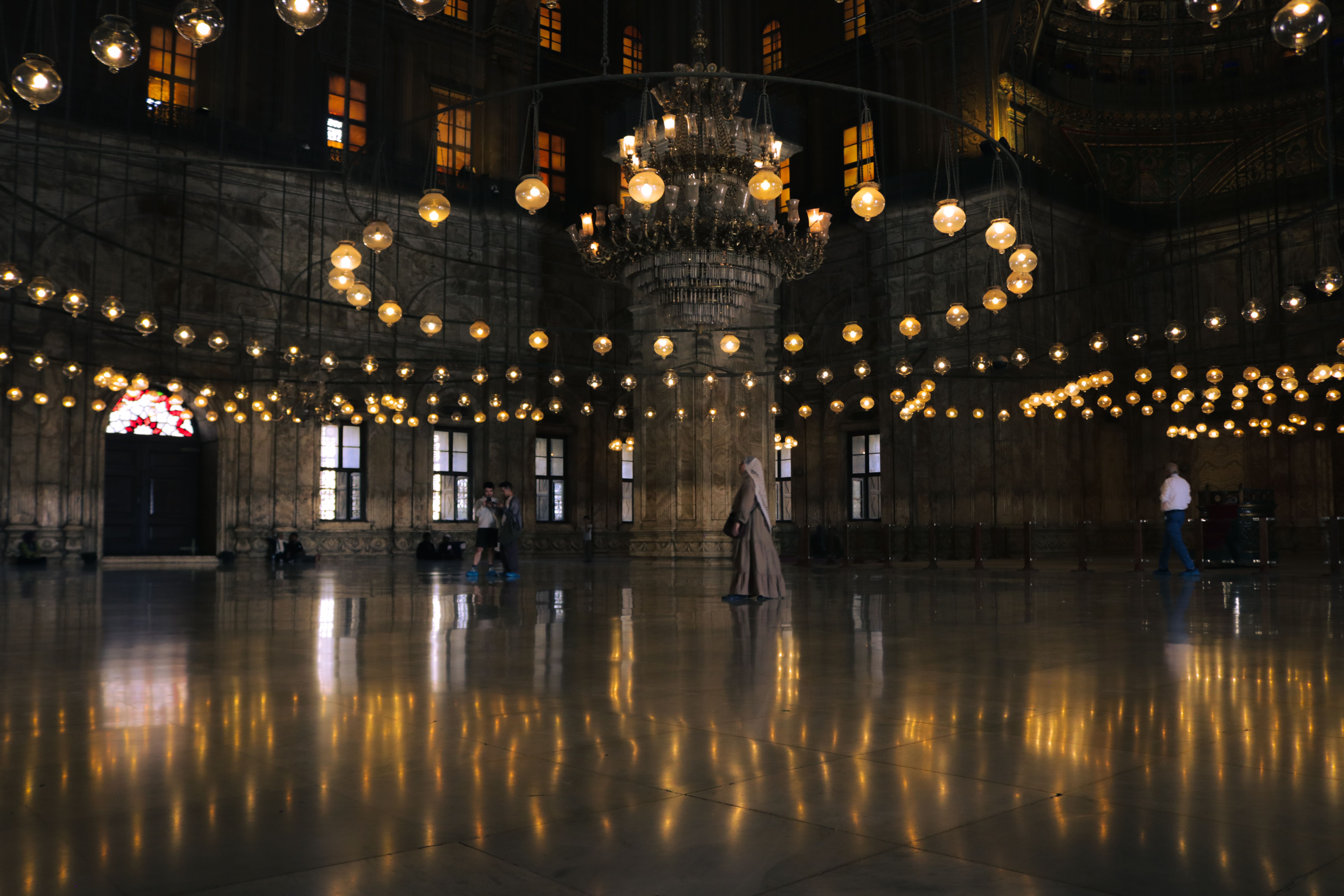 Captivating view of mosque interior in Cairo showcasing chandeliers and reflections.