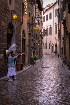 A rainy day on a cobblestone street in Florence, Italy, with people enjoying the ambiance.