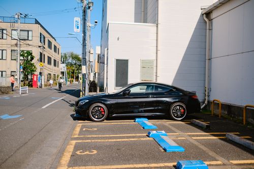Free Black luxury car parked in a city street under bright daylight. Stock Photo