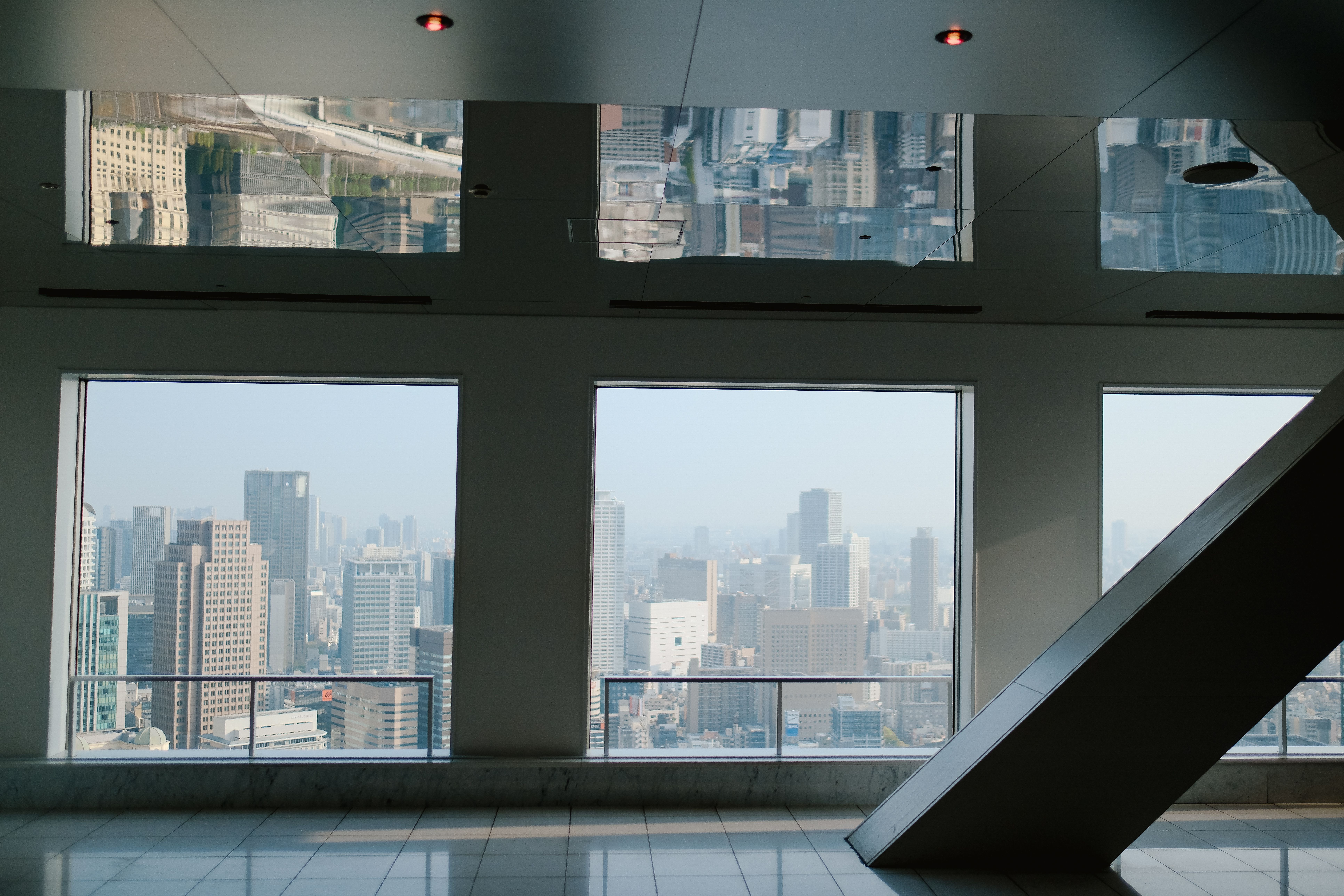A panoramic view of a bustling urban skyline through large window frames inside a modern building.