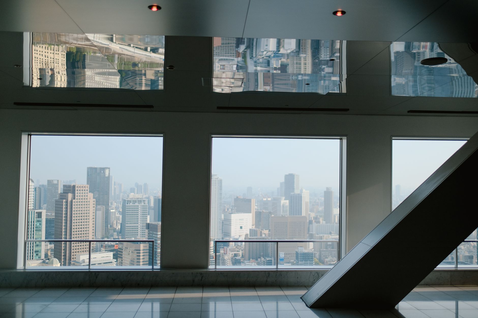 A panoramic view of a bustling urban skyline through large window frames inside a modern building.