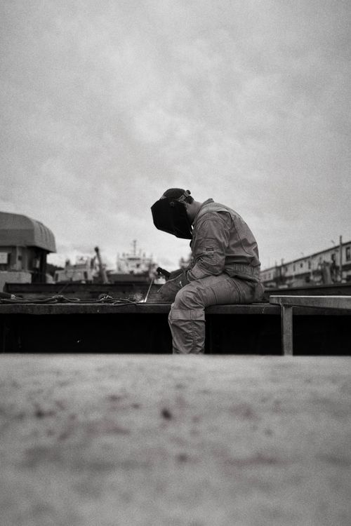Free Silhouette of a welder working in an industrial outdoor setting in black and white. Stock Photo