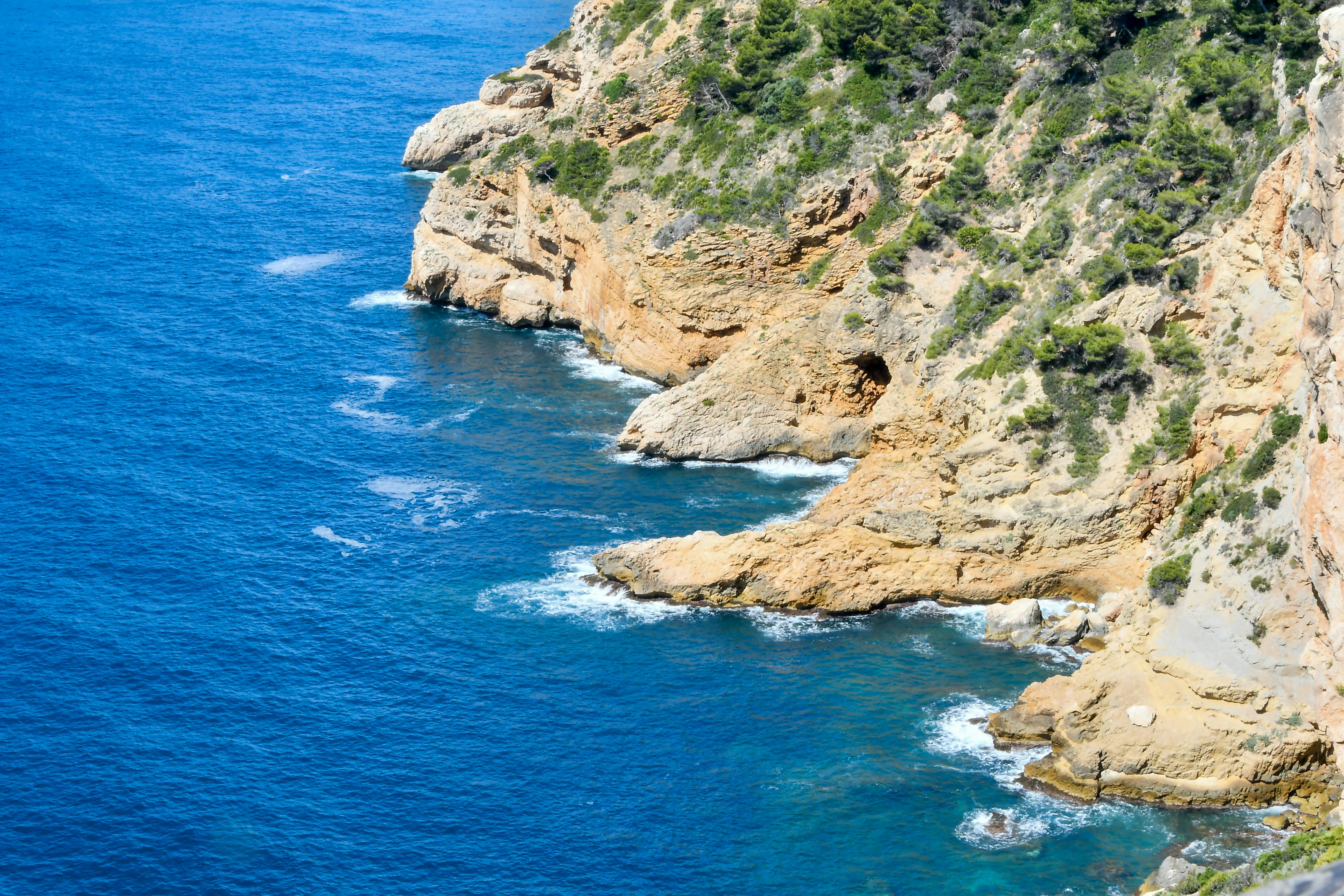 Coastal view of Spain with clear blue water and Mediterranean cliffs in warm afternoon light