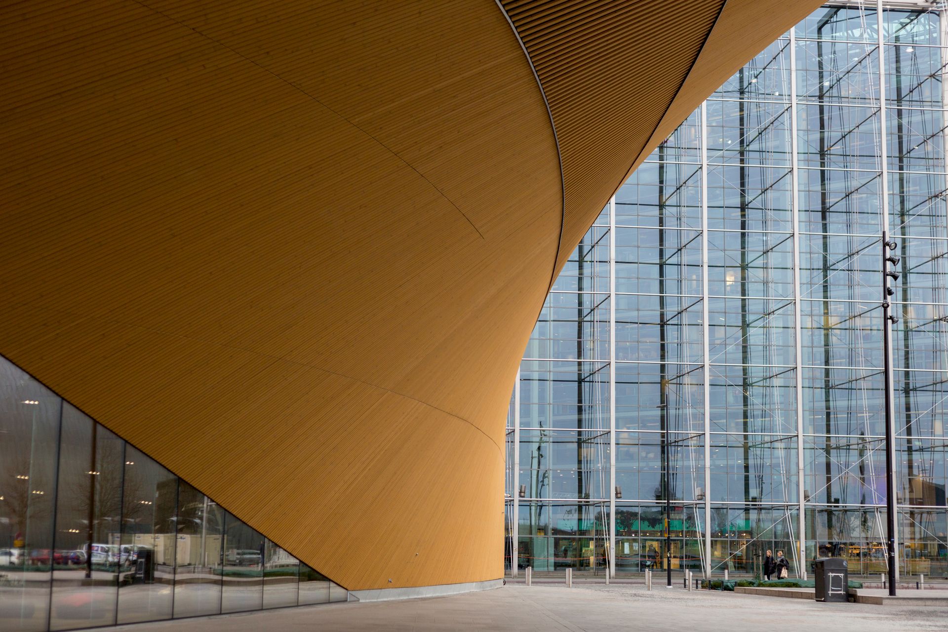 Striking architectural design featuring a wooden curve and glass facade in urban setting.