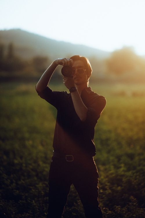 Free A silhouette of a photographer capturing nature during sunset, creating a peaceful ambiance Stock Photo