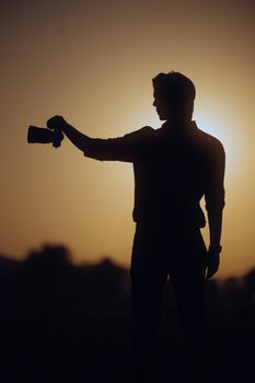 A captivating silhouette of a photographer holding a camera against a sunset backdrop, creating a dramatic scene.