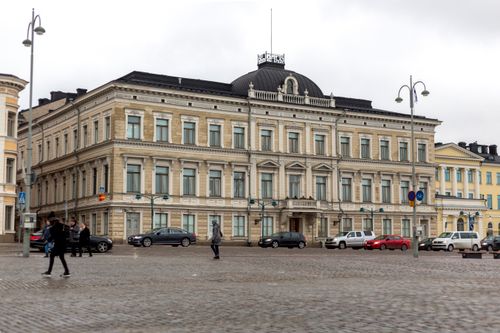 Free Classic European architecture in Helsinki with people walking and cars passing by on a cloudy day. Stock Photo