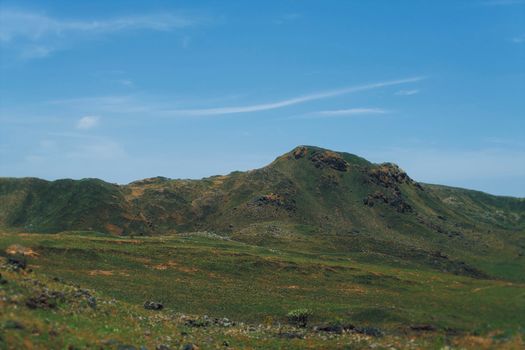 Beautiful green hills and a clear blue sky create a peaceful mountain landscape scene.
