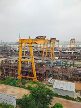 Aerial perspective of an industrial site with large yellow cranes at work.