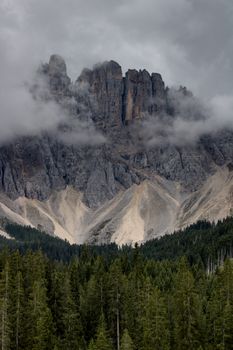 Breathtaking view of the Dolomite Mountains shrouded in mist above a lush forest.