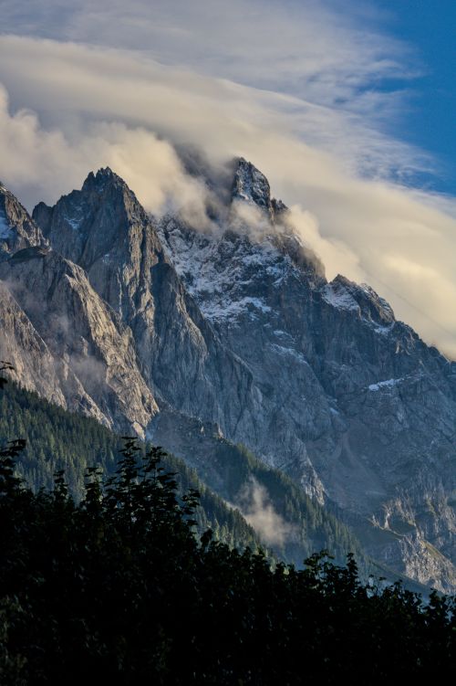 Free Dramatic mountain peaks under a clear blue sky with wispy clouds, creating a picturesque scene. Stock Photo