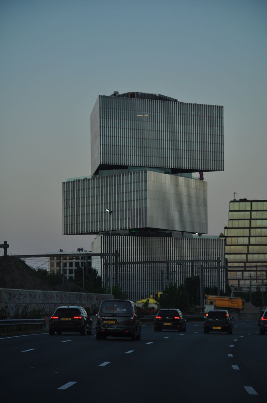 Opvallende moderne architectuur vastgelegd tijdens zonsondergang in Amsterdam, langs een drukke snelweg.