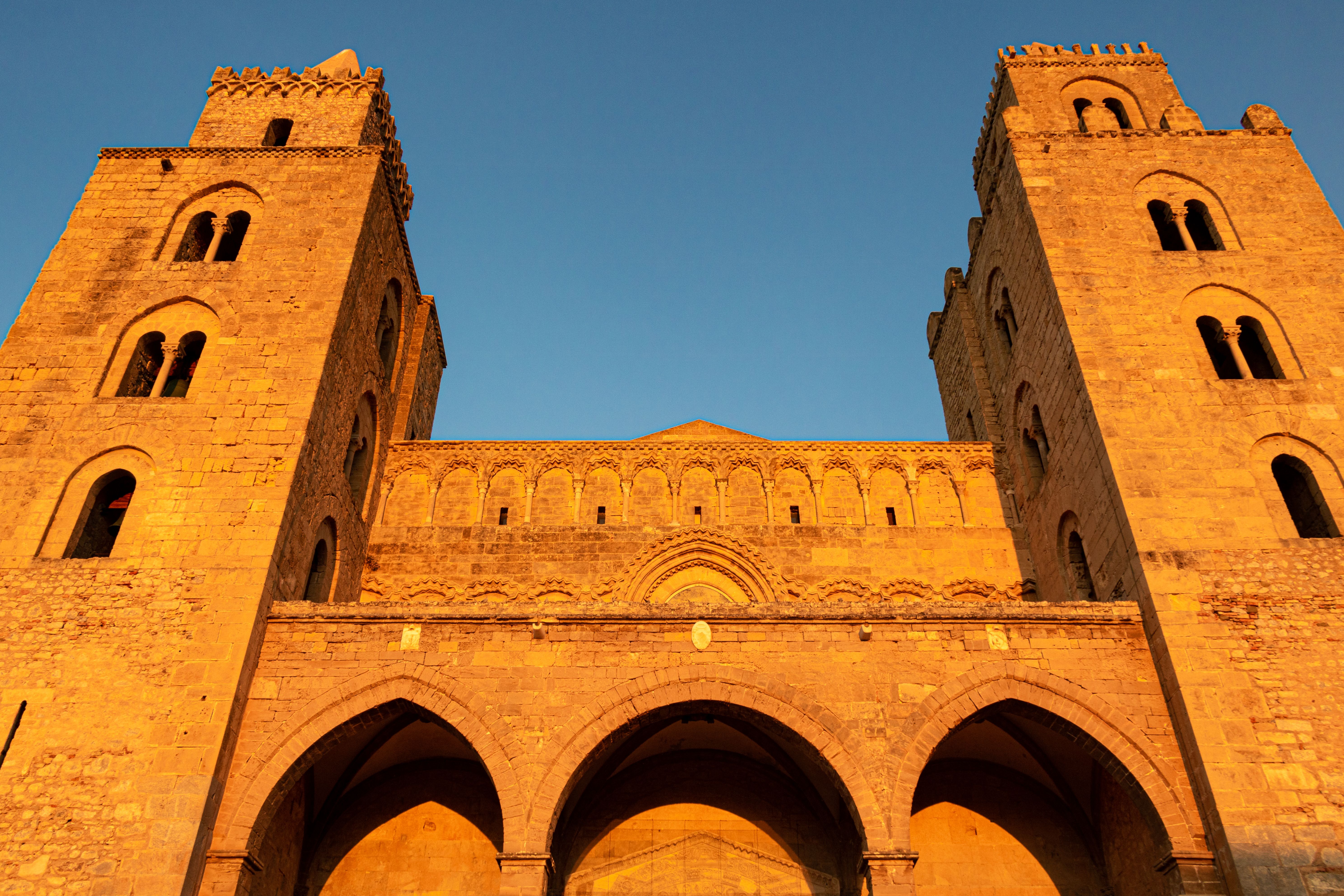 Stunning view of Cefalù Cathedral in Sicily, Italy, illuminated by the warm glow of sunset.