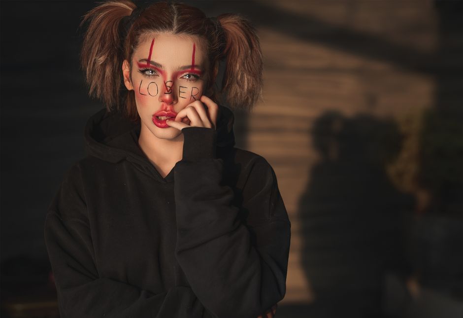 Artistic portrait of a woman with expressive face paint and shadow play, evoking a moody and dramatic atmosphere.