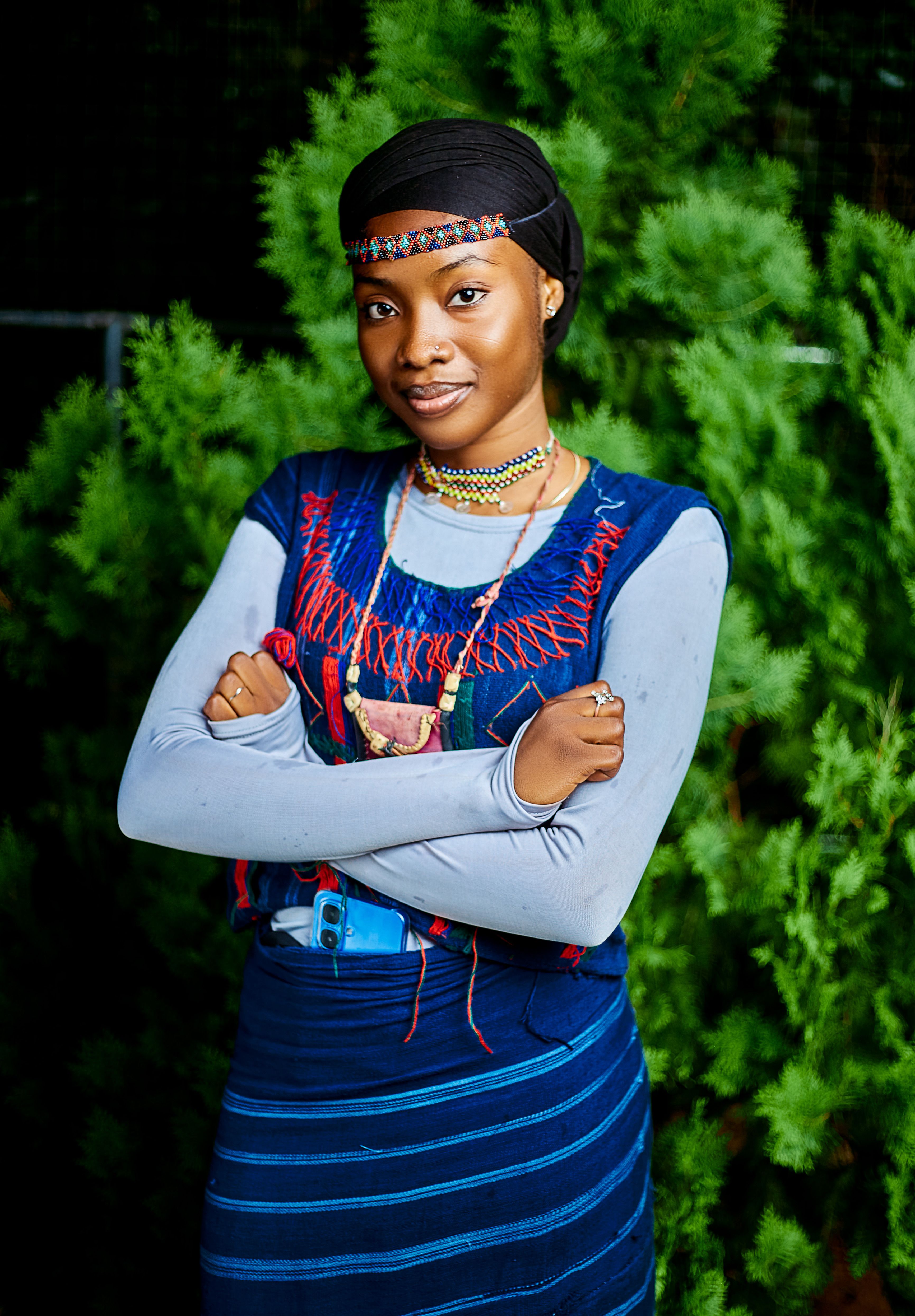 Young woman in colorful traditional attire poses confidently outdoors.