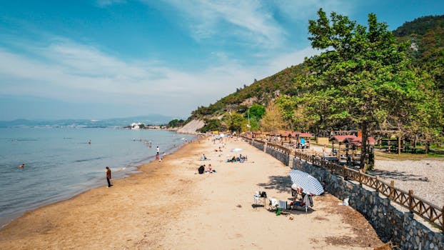 Aerial view of a sunny beach with people enjoying the seaside in Kuşadası, Türkiye.