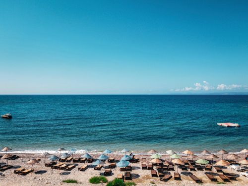 Free Aerial shot of a serene beach in İzmir, Türkiye with colorful umbrellas and lounge chairs. Stock Photo