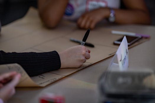 Hands writing on large paper during a collaborative team meeting, emphasizing planning and strategy.