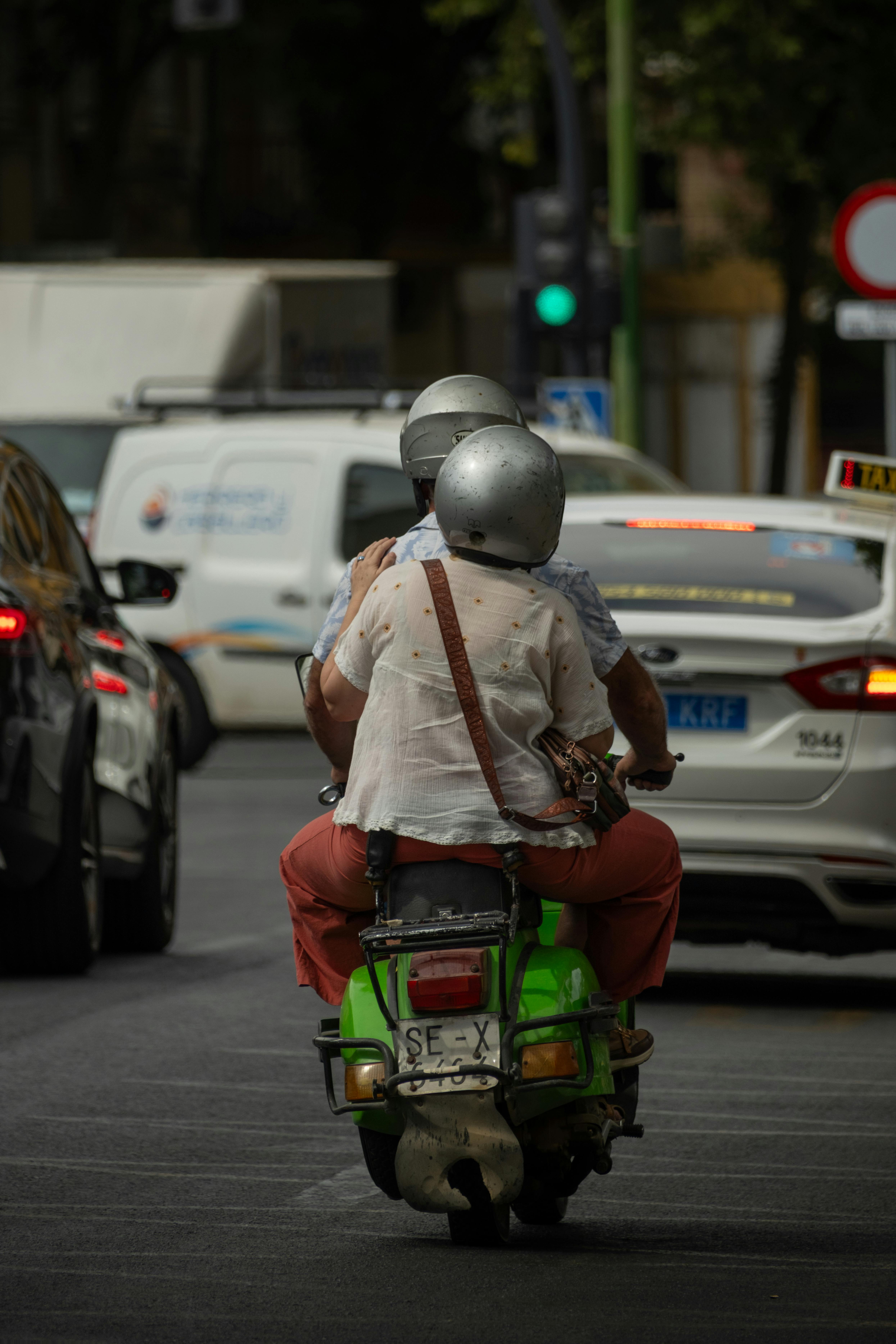 Free Two adults on a motorcycle amid city traffic, capturing urban commuting life. Stock Photo