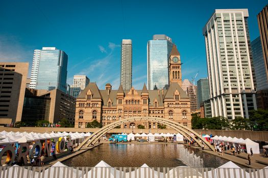 Toronto's historic Old City Hall and Nathan Phillips Square with reflecting pool under blue sky.