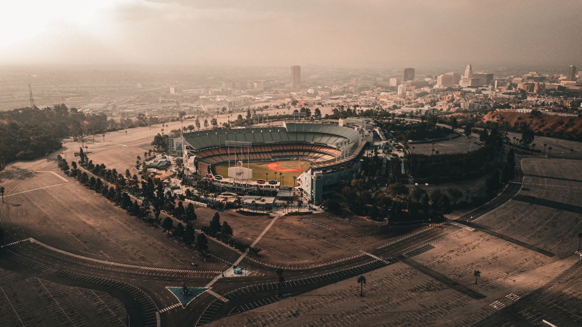 Captivating aerial view of Dodger Stadium and downtown Los Angeles under a dramatic sky.