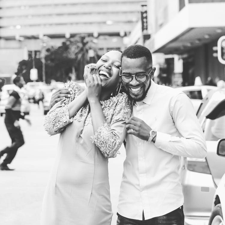 Grayscale Photography Of Man And Woman Standing And Laughing