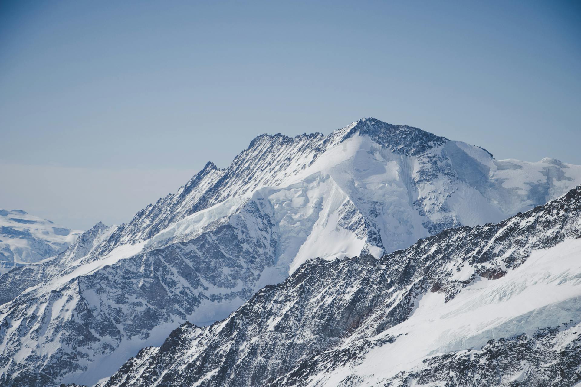 Stunning view of snow-covered Alps in Switzerland beneath a clear blue sky, capturing the essence of winter beauty.