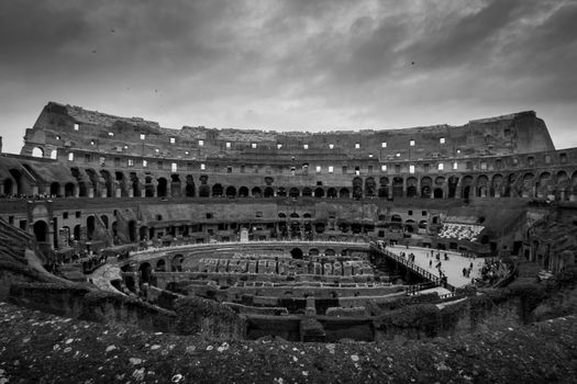 Dramatic black and white photo of the Colosseum interior, Rome, Italy.