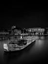 一张迷人的单色图像，拍摄于柏林运河的夜晚，画面中是一艘废弃的船只