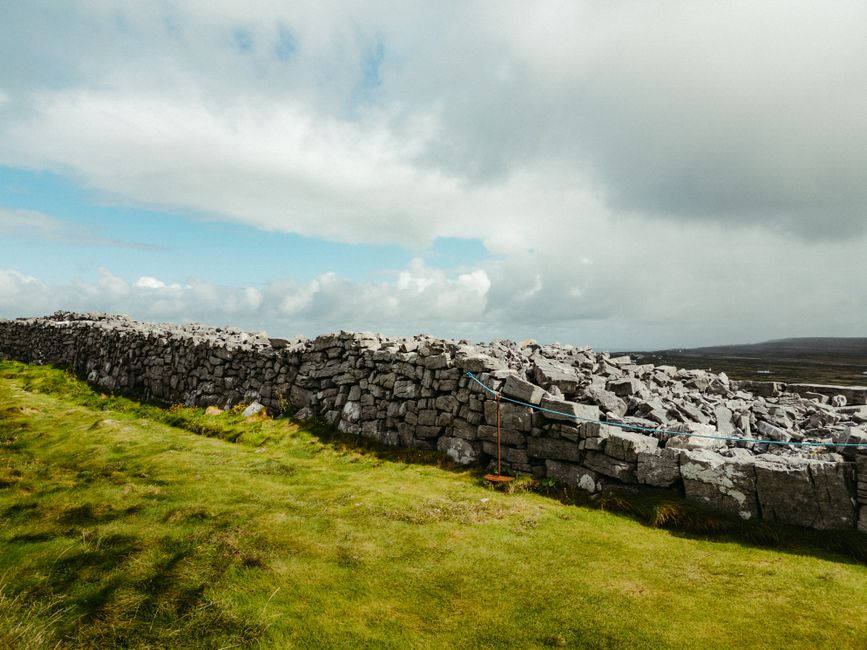 A scenic shot of a traditional stone wall in County Clare, Ireland under a cloudy sky. A scenic shot of a traditional stone wall in County Clare, Ireland under a cloudy sky.