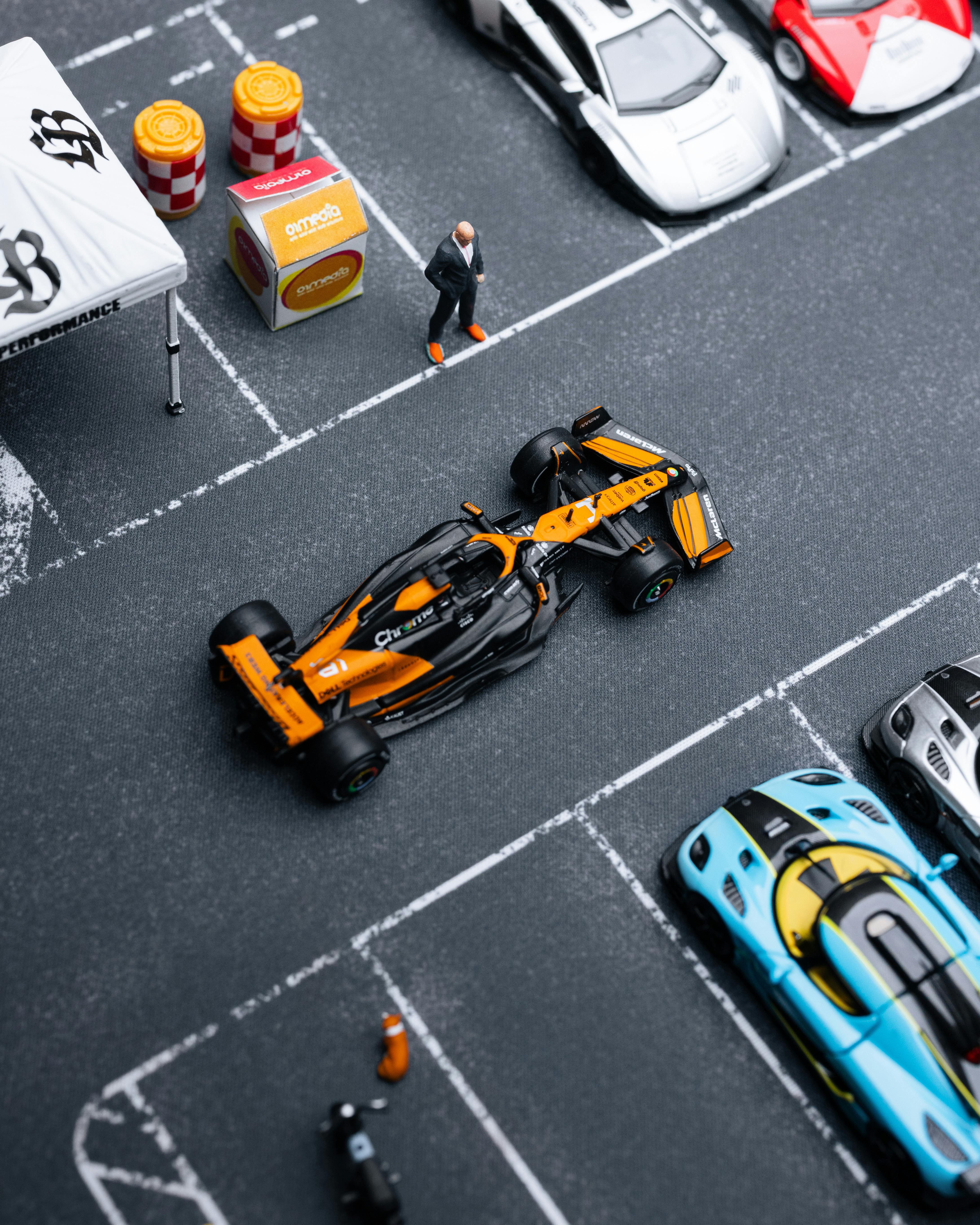 Gratis Model mobil miniatur yang rumit dalam tata letak parkir, menampilkan mobil balap dan aksesori mendetail. Foto Stok