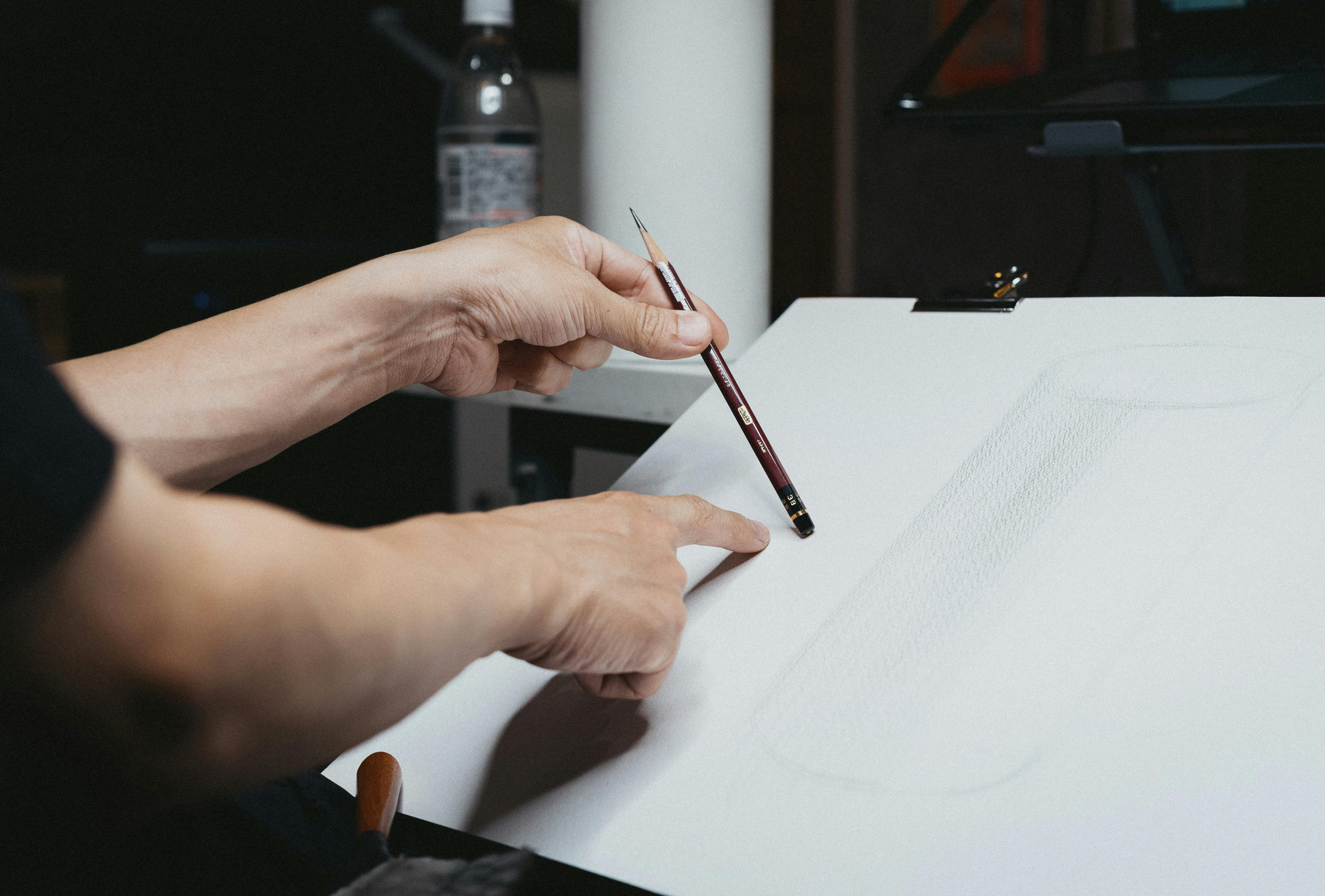 Gratis Primer plano de un artista dibujando con lápiz durante una sesión creativa en el interior, centrándose en la expresión artística. Foto de stock