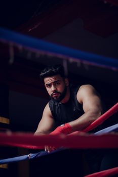 Portrait of a male boxer taking a break between rounds in a boxing ring.