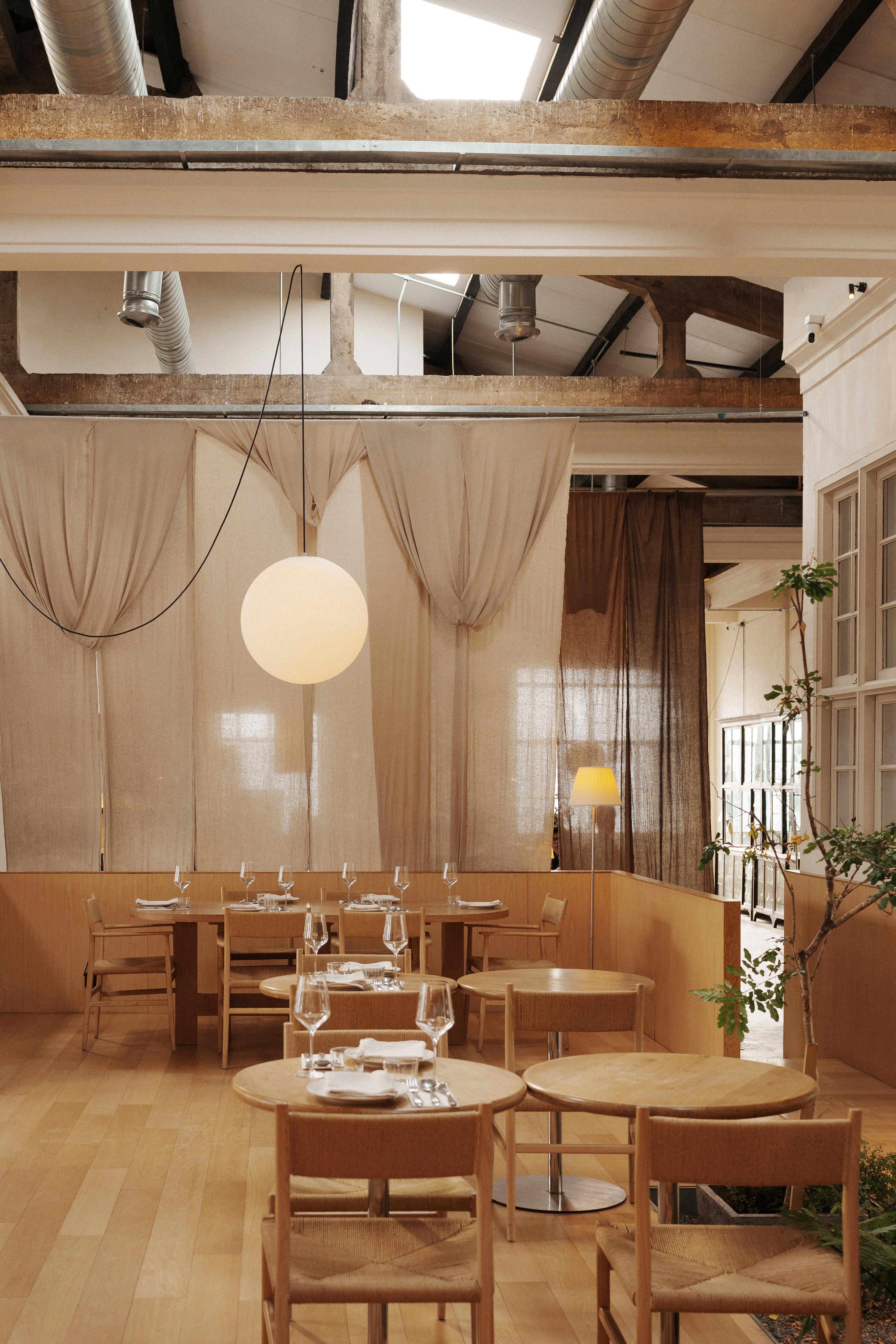 Chic industrial-style restaurant interior with wooden furniture and ambient lighting in George Town, Malaysia.