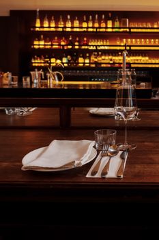 Close-up of a finely set dining table with glassware in a cozy bar setting.