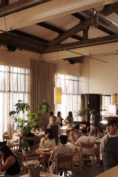 A warmly lit cafe with patrons enjoying meals in George Town, Malaysia.